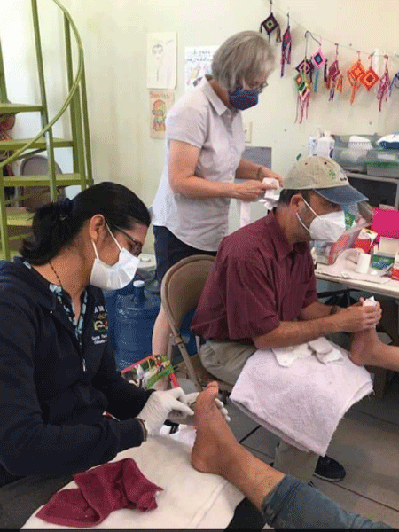 La hermana Maribel Lara y el Dr. Marino cuidan los pies de las personas que han venido al Centro de Recursos para Migrantes. (Foto por la hermana Judy Bourg)