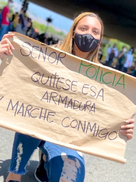 Un manifestante en Medellín sostiene un cartel que dice: “Sr. policía, quítese la armadura y marche conmigo”. (Foto por Edwin Dávila)