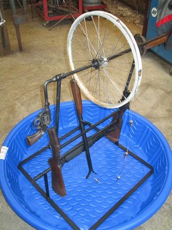 Rope pump crafted from from an AR 15 rifle, a .38 caliber handgun, and two single-barrel shotguns.