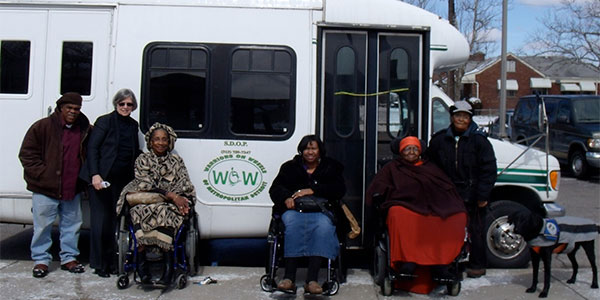 People sitting in wheelchairs in front of SDOP van