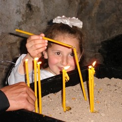 Young girl lights a prayer candle