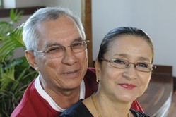 Photo of Andres and Gloria Garcia. He is wearing a black robe, clerical collar and purple stoll. She is wearing traditional African dress with head covering.